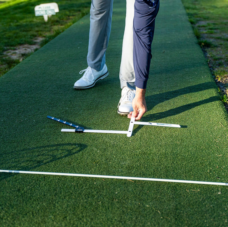 Golfer aligning stance caddy against the target line marked by an alignment stick